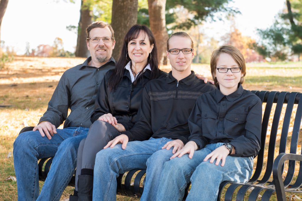 Father, mother, and two sons sit on a bench