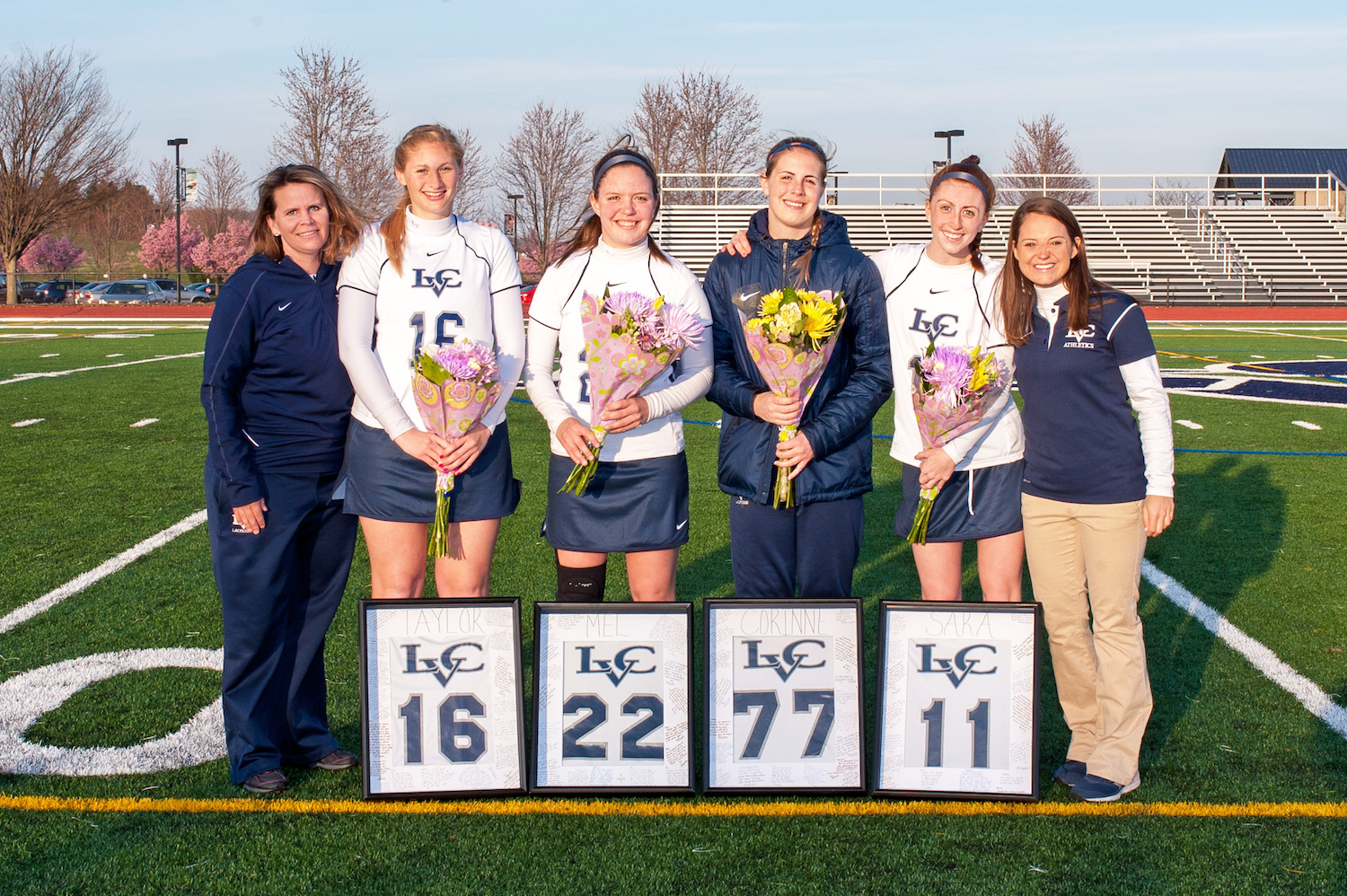 Women holding flowers posing on football field